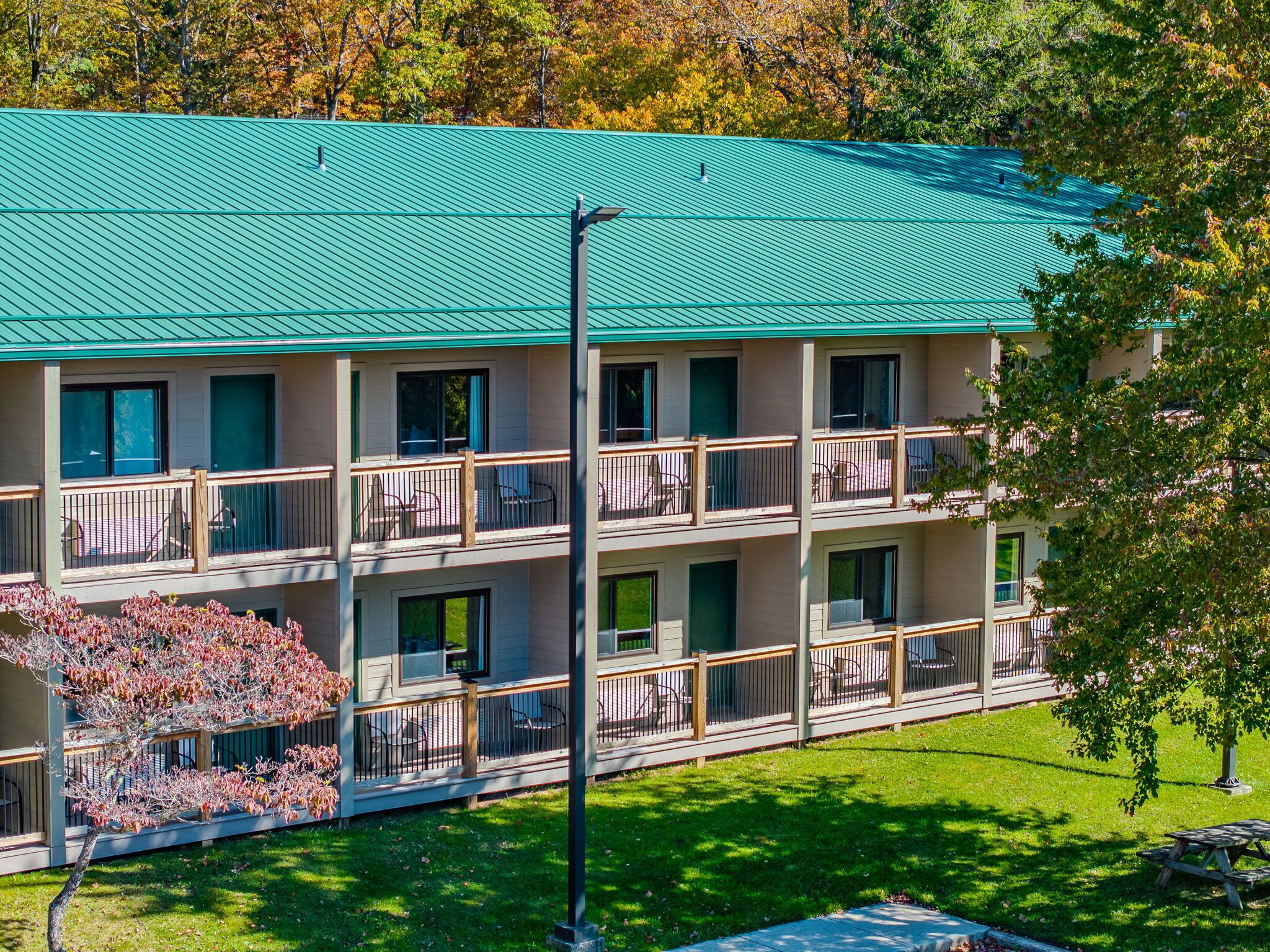 A multi-story hotel with a green roof, balconies with railings, and a well-maintained lawn.
