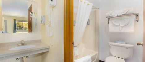 Un baño con lavamanos, secador de pelo, cortina de ducha, bañera y retrete.