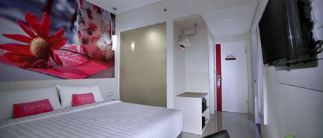 A hotel room with a large bed, a television, a small desk, and a bathroom visible through an open door.