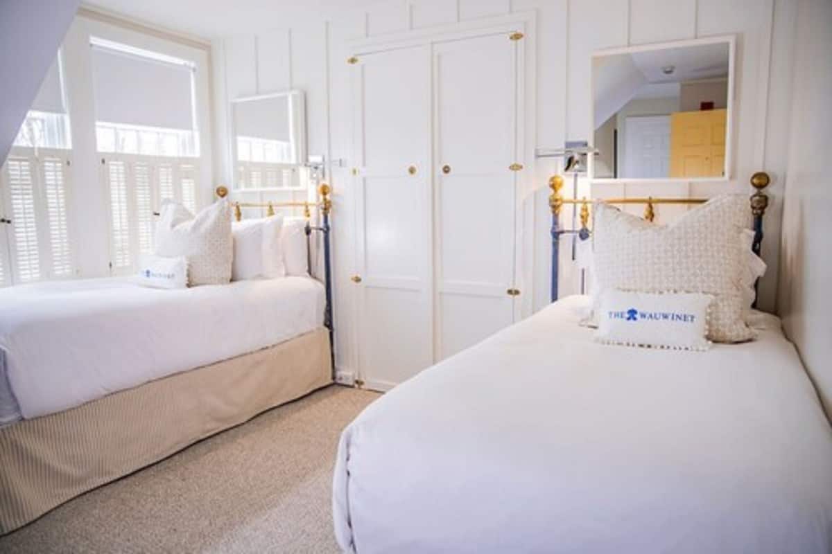 Une chambre d’hôtel avec deux lits, une grande fenêtre, un miroir et une armoire.