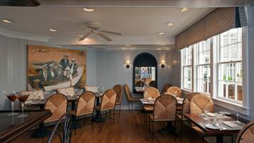 Un restaurante con suelo de madera, sillas tapizadas y un mural grande en la pared.