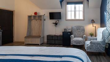 A bedroom with a bed, a wardrobe, a chair, a desk, a TV, and a window.