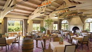 A spacious dining area with multiple tables and chairs, a large wooden barrel, and a fireplace. - Napa Valley Lodge (Yountville)