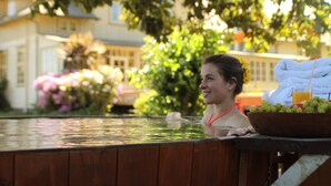 Una persona en un jacuzzi con un cuenco de fruta y una toalla sobre una mesa de madera.