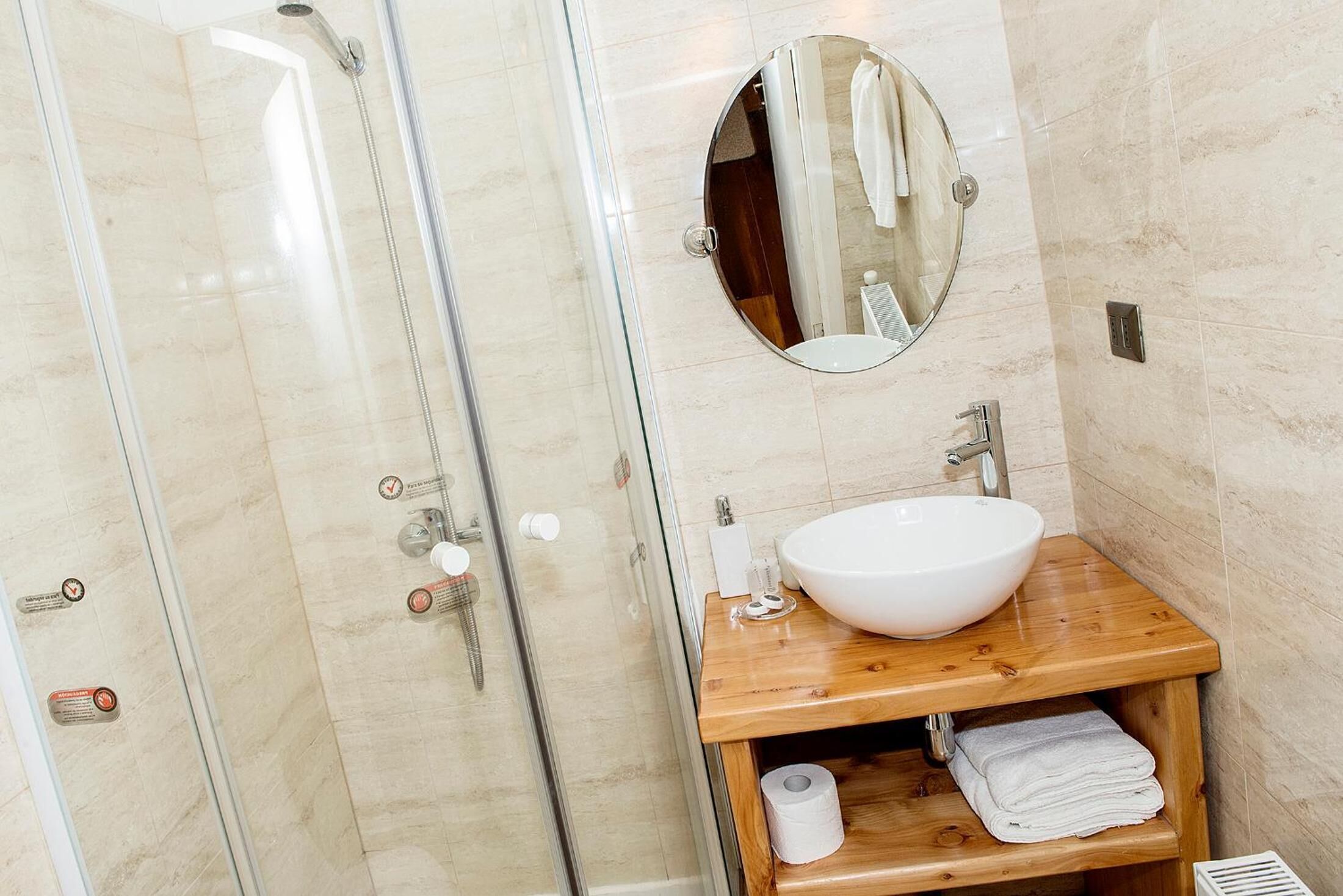 A bathroom with a glass-enclosed shower, a wooden vanity with a white sink, and a mirror above the sink.