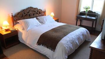 A neatly made bed with a wooden headboard, two bedside lamps, and a small table with a vase of flowers.