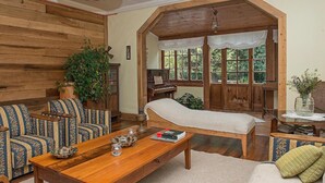 Una habitación acogedora con un banco de madera, un sofá y una cama bajo un arco de madera.