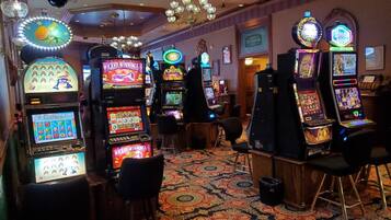 Une salle de casino avec des machines à sous, des tabourets de bar et une moquette à motifs.