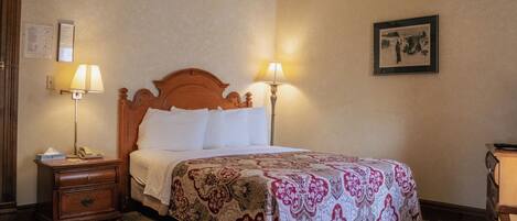 A hotel room with a wooden bed, two bedside lamps, a nightstand, a dresser, and a framed picture on the wall.