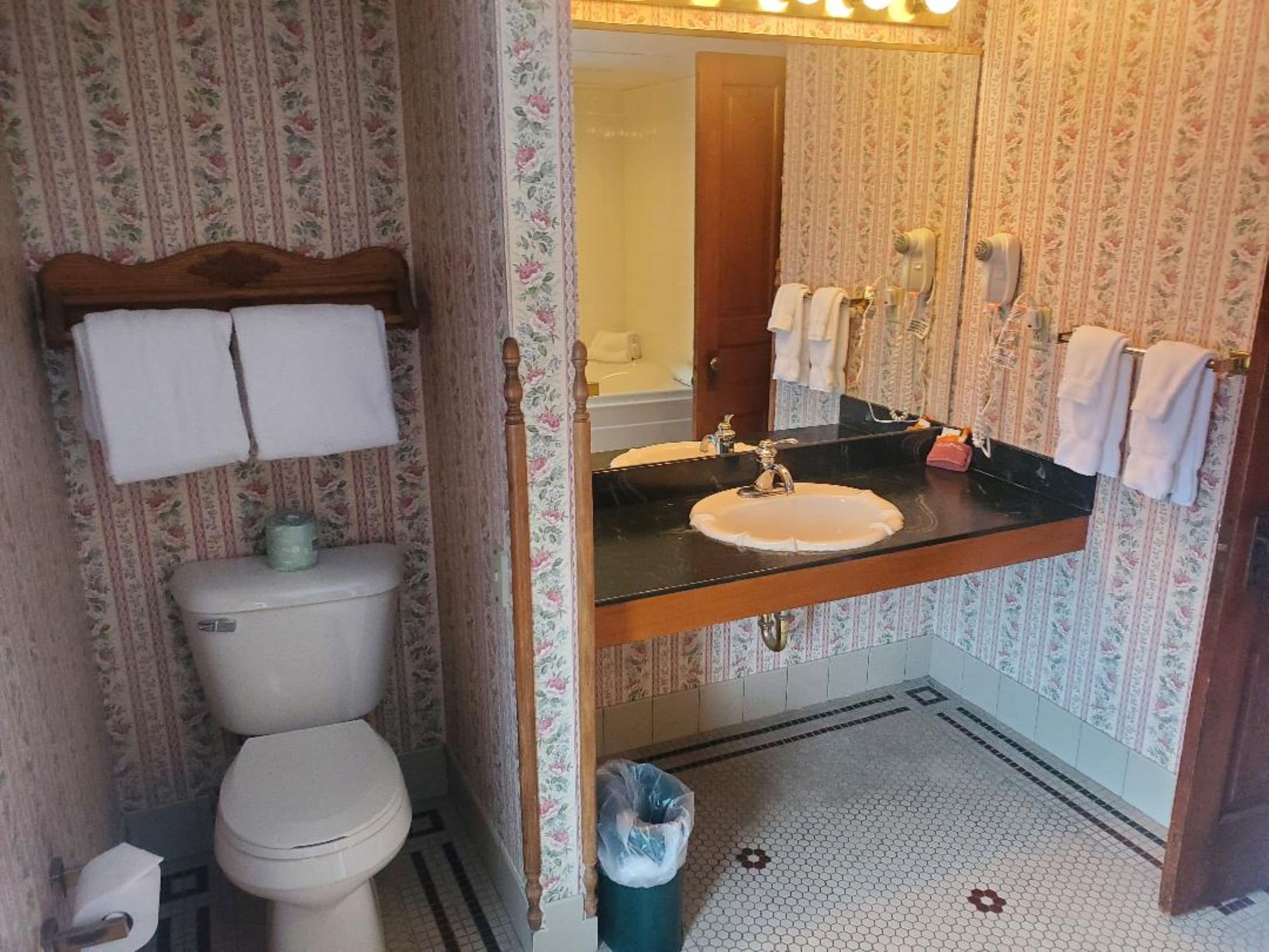 A bathroom with a toilet, sink, and mirror.