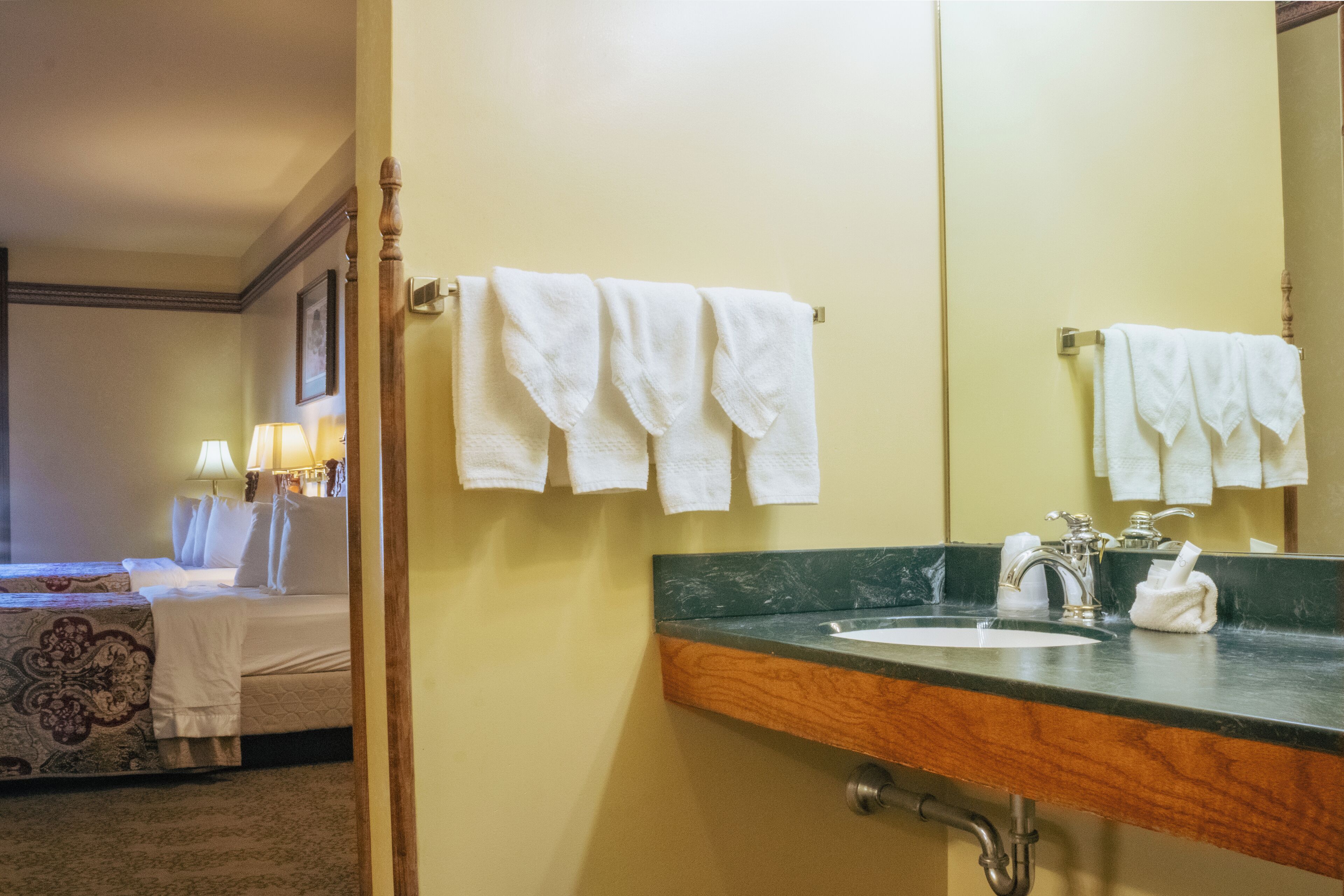 Une salle de bain d’hôtel avec un lavabo, un miroir et des serviettes accrochées au mur.