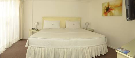 A hotel room with a large bed, two bedside tables, a flat-screen TV, and a painting on the wall.