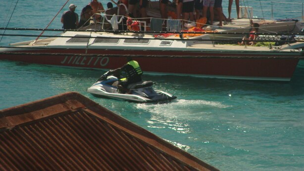 A boat with a red canopy and people on deck. - Coral Lane Beach Apartments (Paynes Bay)