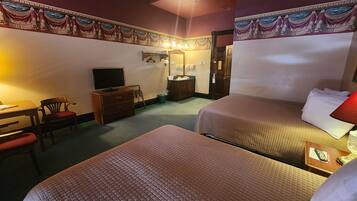 A hotel room with two beds, a desk with a chair, a television, a dresser, and a door.