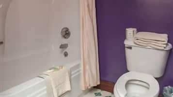 A bathroom with a bathtub, toilet, and a shower curtain.