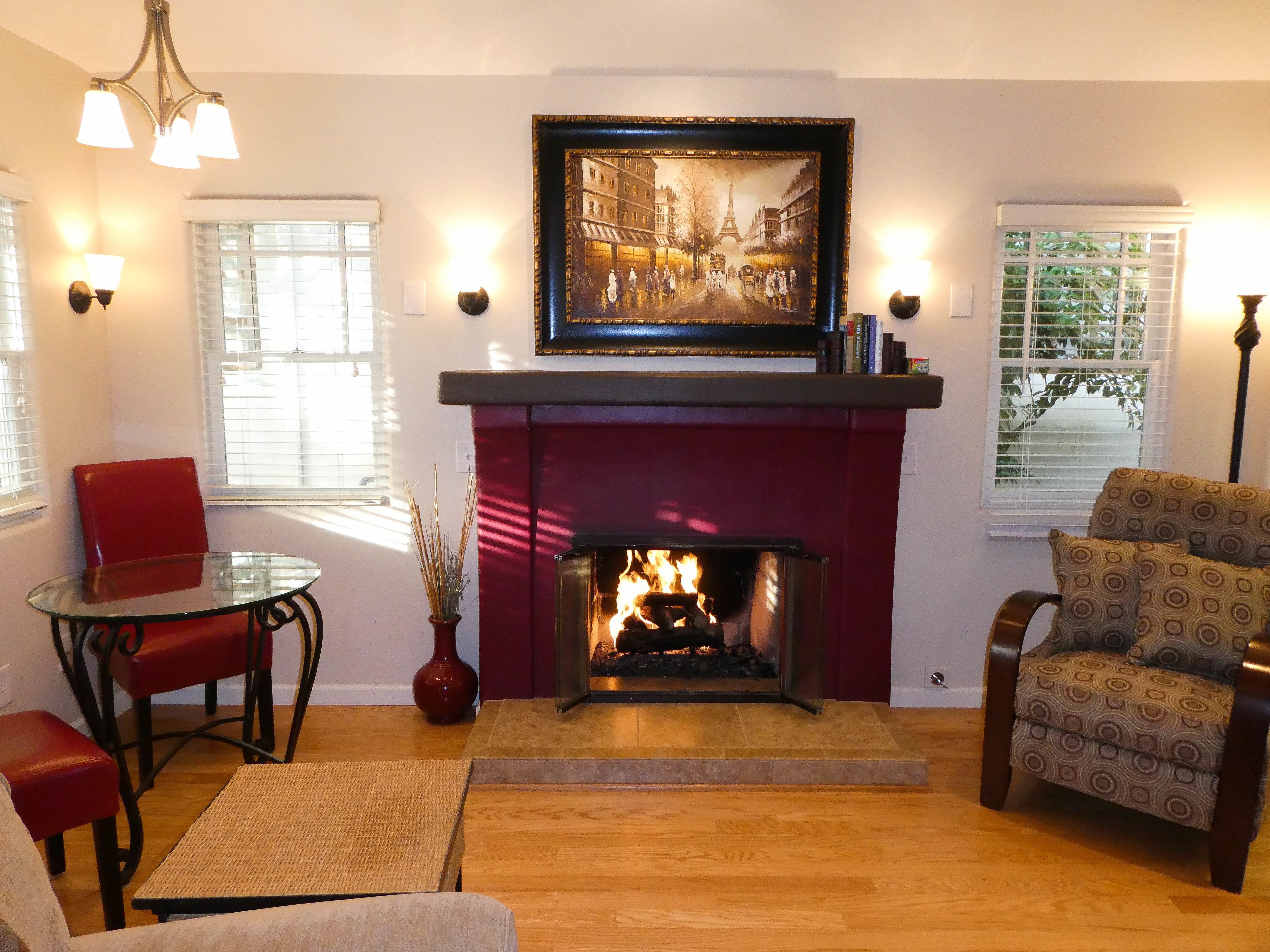 A living room with a fireplace, a dining table, and two chairs.