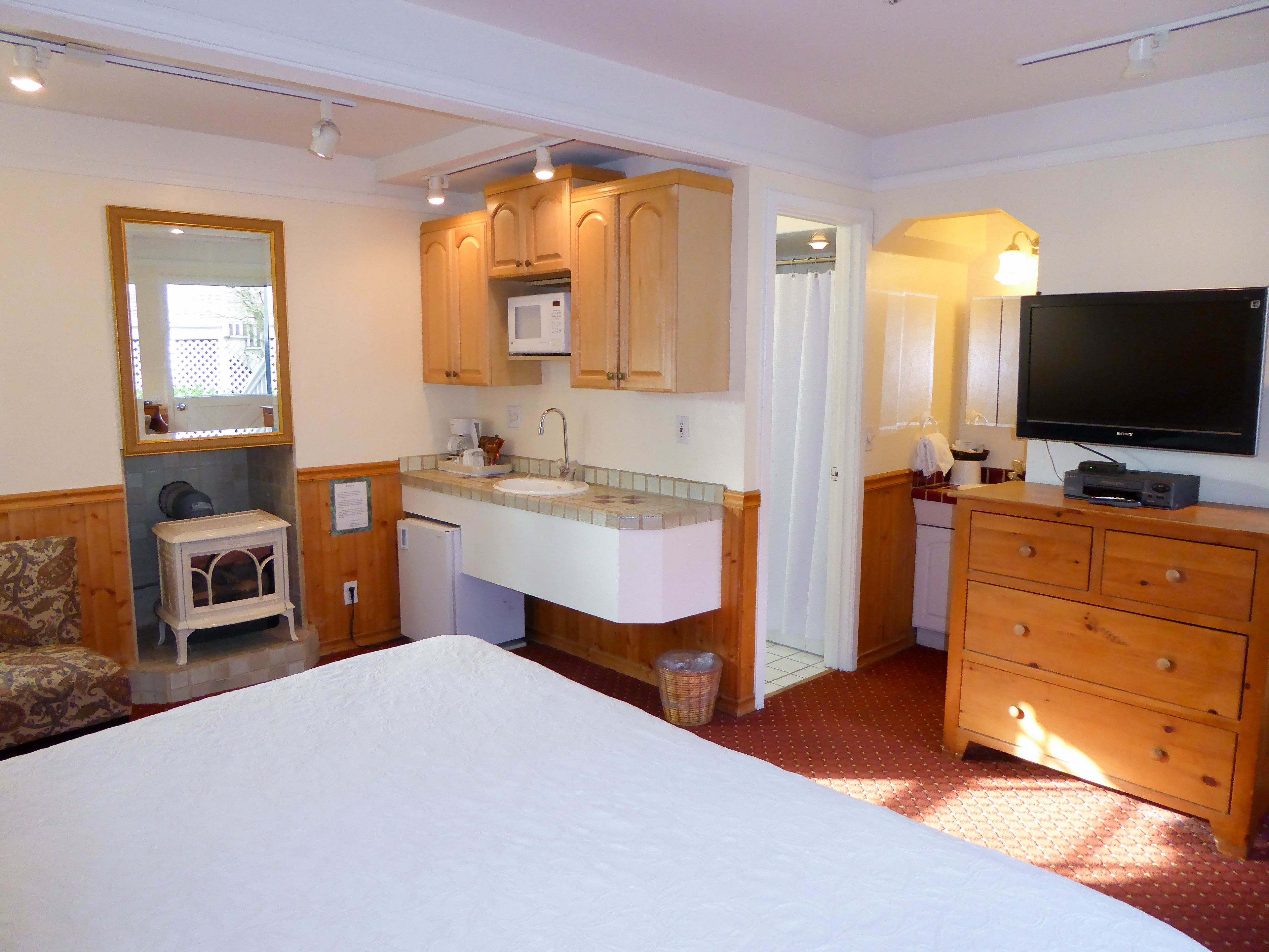 Une chambre d’hôtel équipée d’un lit, d’un lavabo, d’armoires en bois, d’une télévision et d’un miroir.