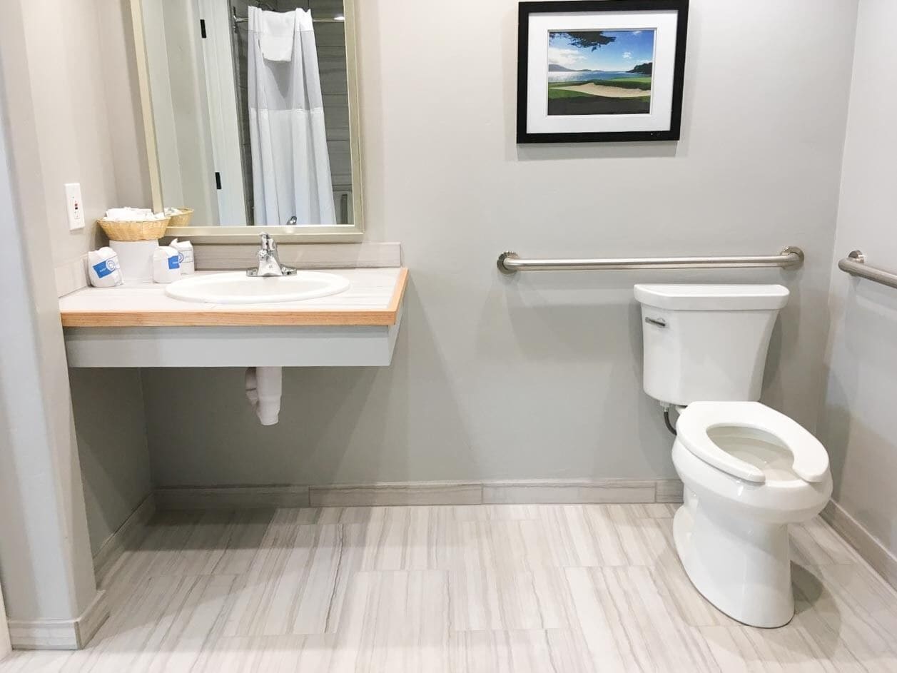 Um banheiro moderno com pia branca, vaso sanitário e um quadro na parede.