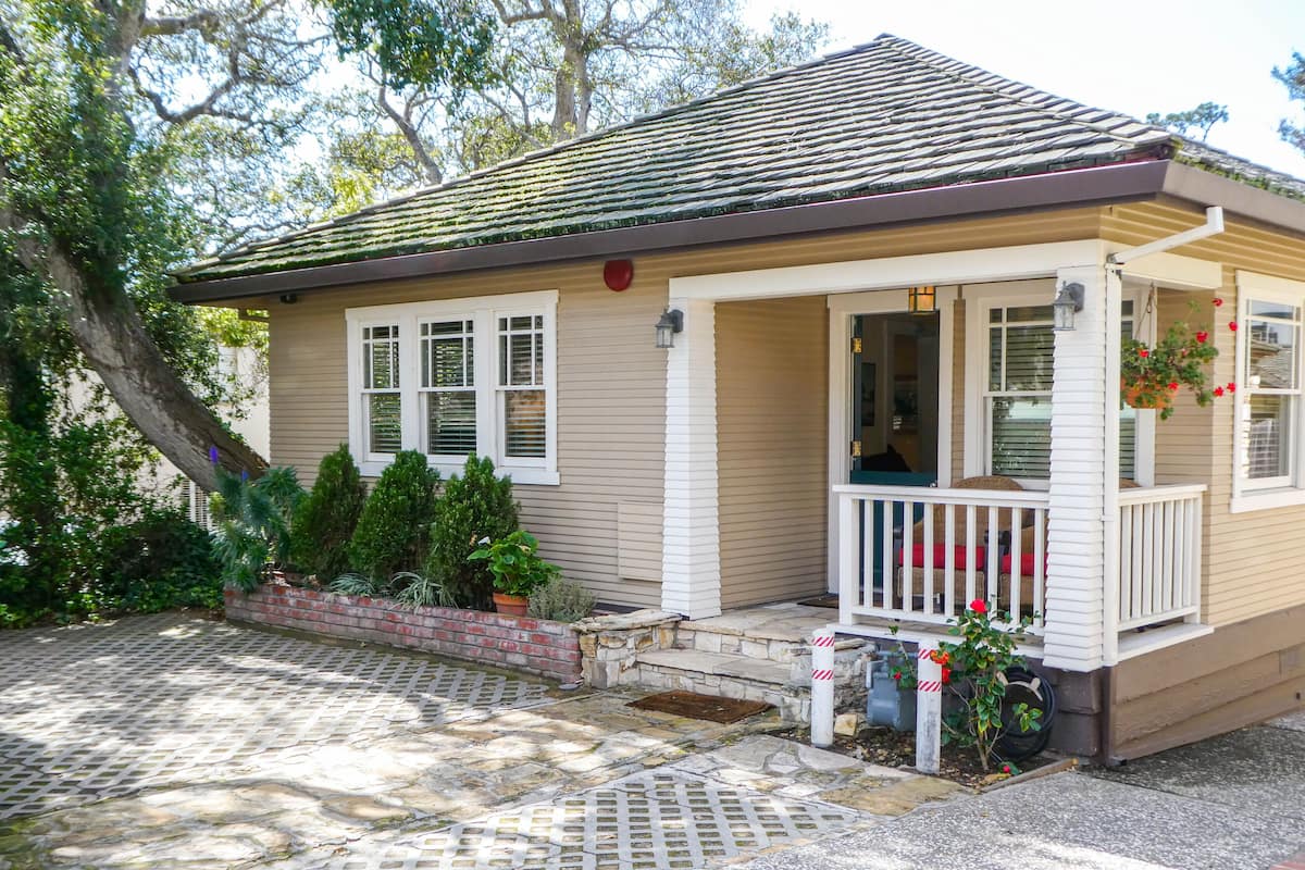 A single-story house with a porch, a brick foundation, and a tiled roof.