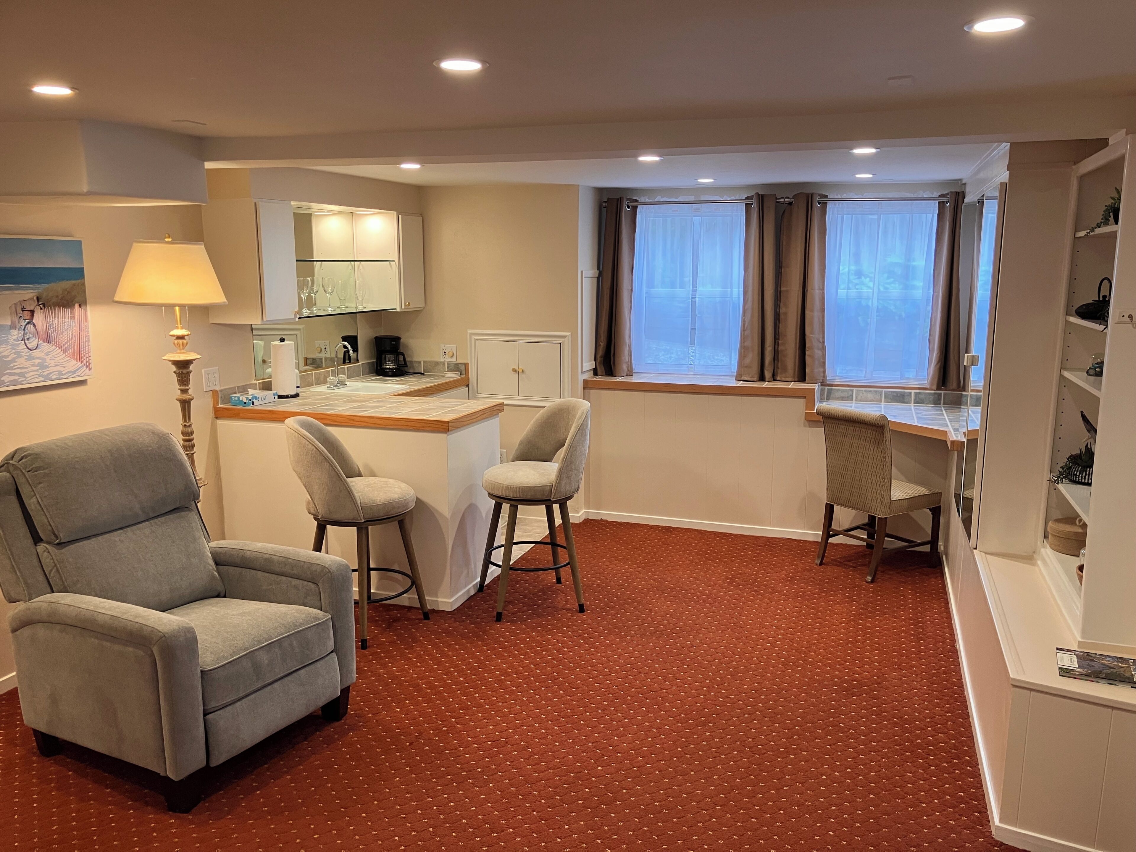 Une chambre d’hôtel équipée d’une kitchenette, d’un coin repas avec un tabouret de bar, d’un canapé et d’un bureau avec une chaise.