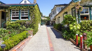 A narrow street lined with two-story houses, one with ivy-covered walls and the other with a brick pathway leading to a door. - Briarwood Inn (Carmel)