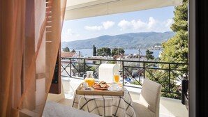 Un balcón con una mesa dispuesta para el desayuno, con vistas a un paisaje montañoso y un lago.
