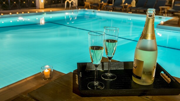 Escena junto a la piscina con una botella de champán y dos copas sobre una bandeja.