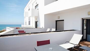 Un área de estar moderna al aire libre con una mesa y sillas, con vistas a un cuerpo de agua.