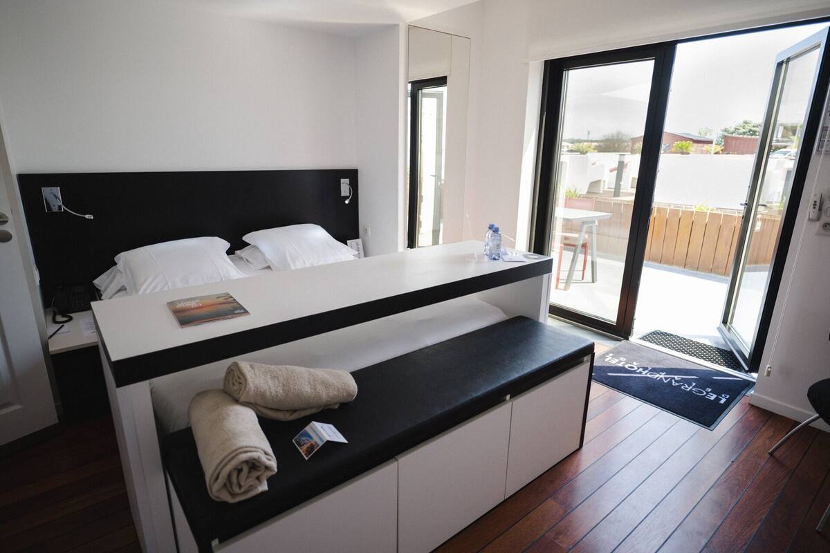 Une chambre moderne avec un lit, un petit bureau et une vue sur l’extérieur.