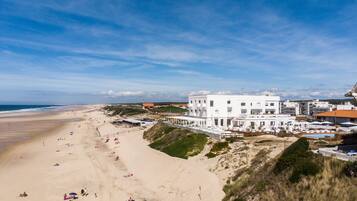 Un hôtel situé sur la côte, doté d’un toit plat, de nombreux balcons et offrant une vue sur la plage.