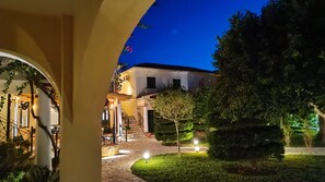 A courtyard with a stone pathway, a small tree, and a building with a staircase leading to a door. - Elanthi Village Hotel (Zakynthos)