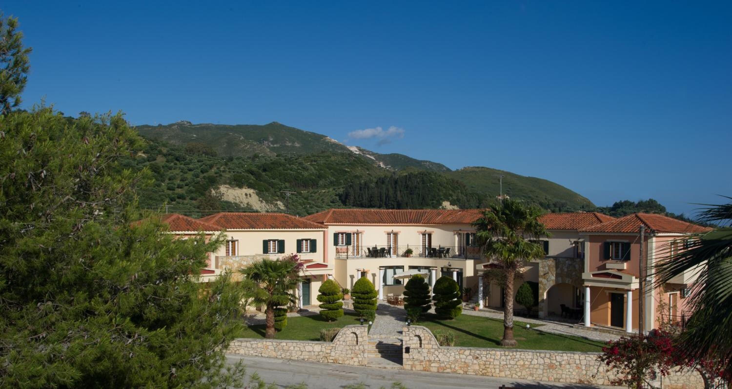 A row of Mediterranean-style villas with terracotta roofs, stone walls, and a central courtyard.