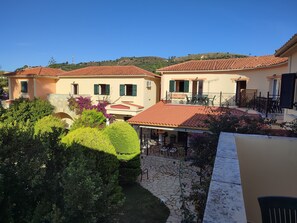 A courtyard with a tiled roof, outdoor seating, and a view of the surrounding landscape. - Elanthi Village Hotel (Zakynthos)