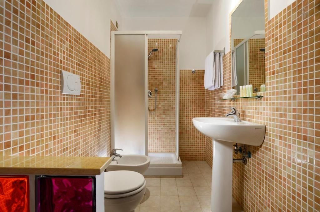 A bathroom with a shower, toilet, bidet, and sink.