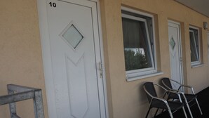 A building facade with numbered doors, windows, and outdoor seating. - Messe Motel Laatzen (Laatzen)