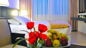 Une chambre d’hôtel avec un lit, une table de chevet, une télévision et un panier de fruits posé sur la table de chevet.
