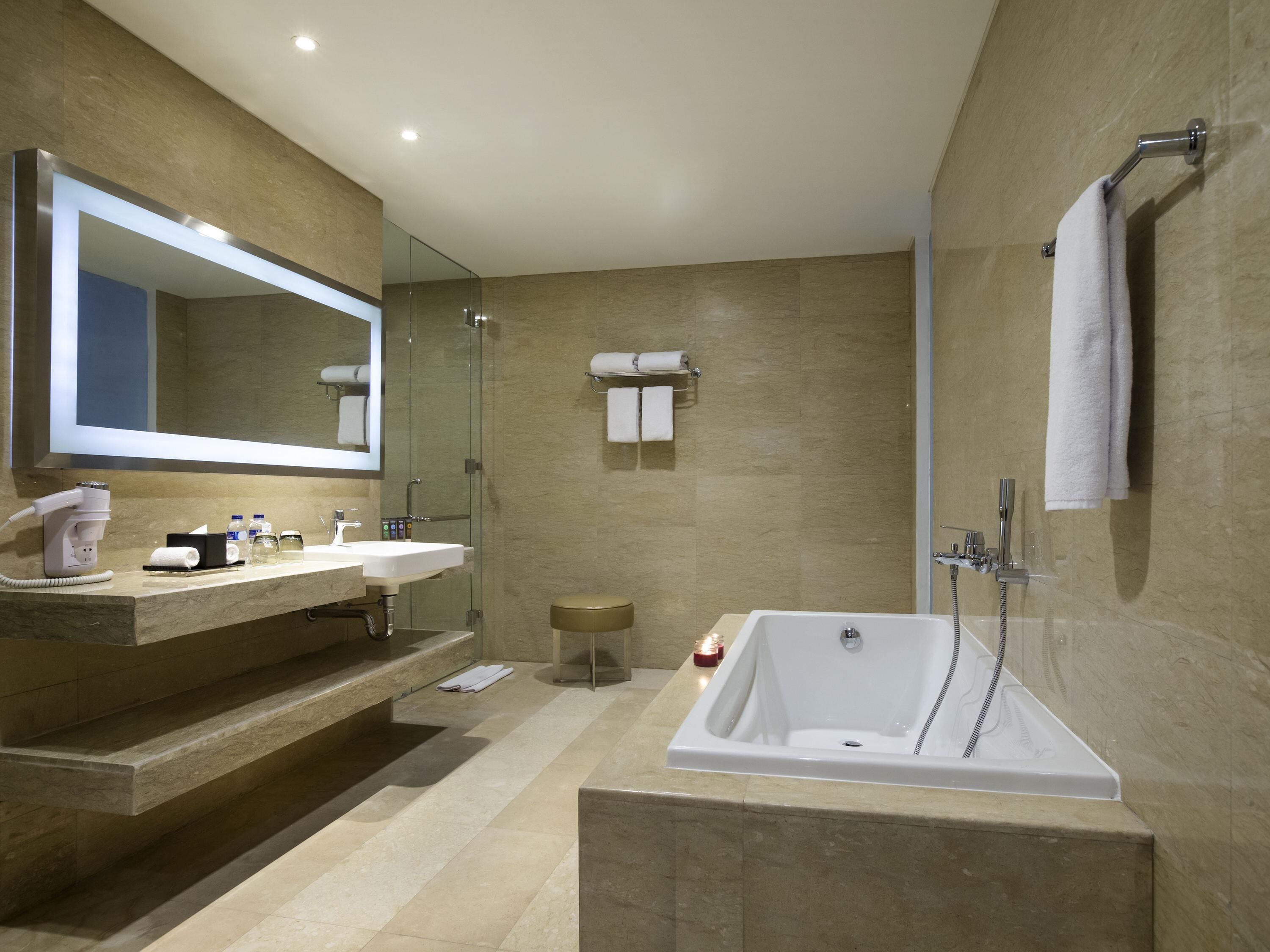 A modern bathroom with a large bathtub, two sinks, a mirror, and a shower.