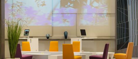 A modern lobby with a reception desk, seating area, and a large projection screen displaying floral patterns.