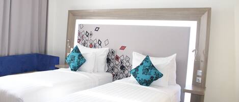 A hotel room with two beds, a blue sofa, and a patterned wall.