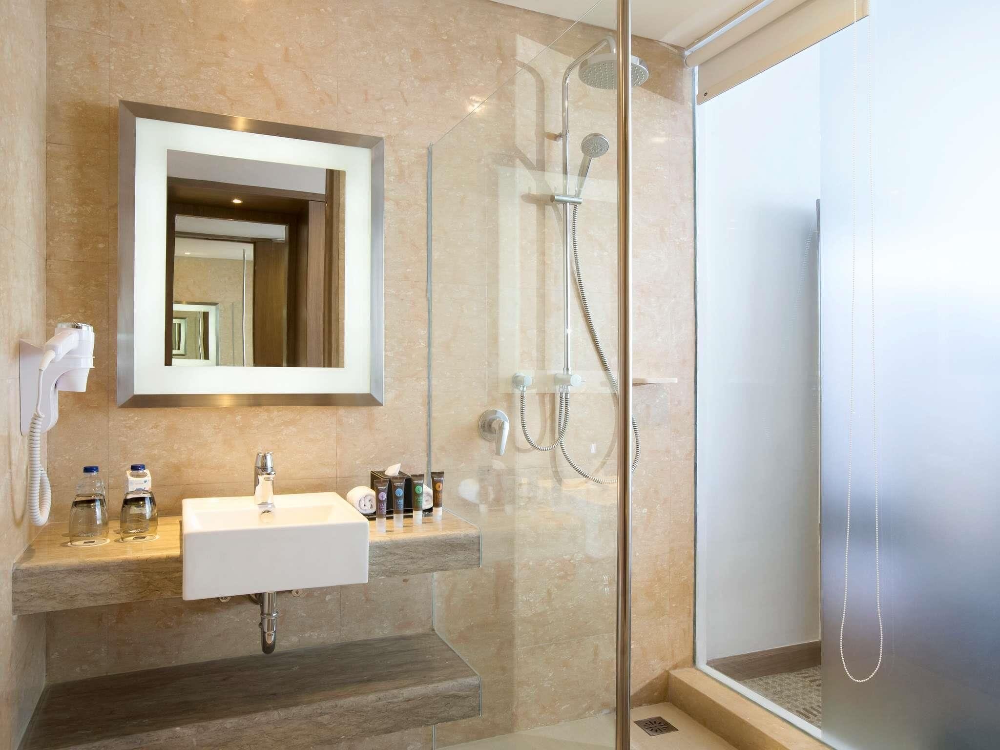 A modern bathroom with a glass-enclosed shower, a white sink, and a large mirror.