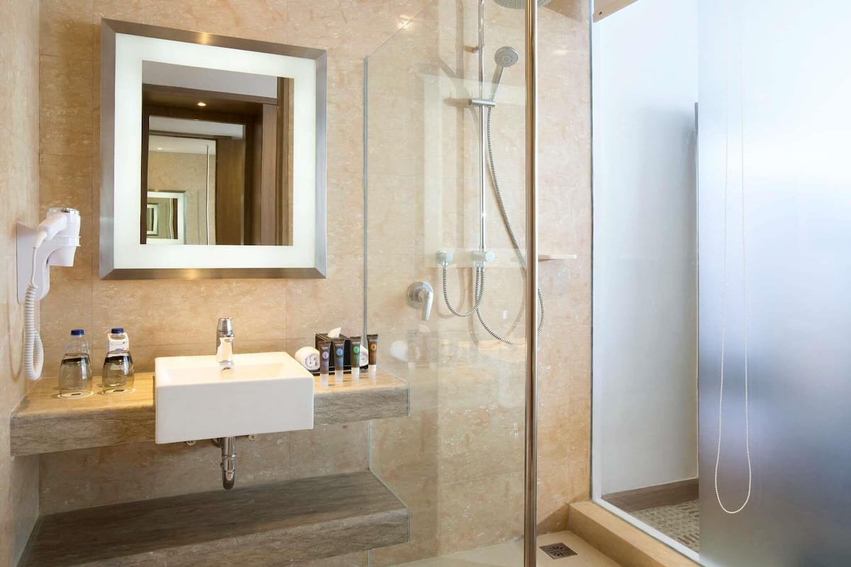 A modern bathroom with a glass-enclosed shower, a white sink, and a large mirror.