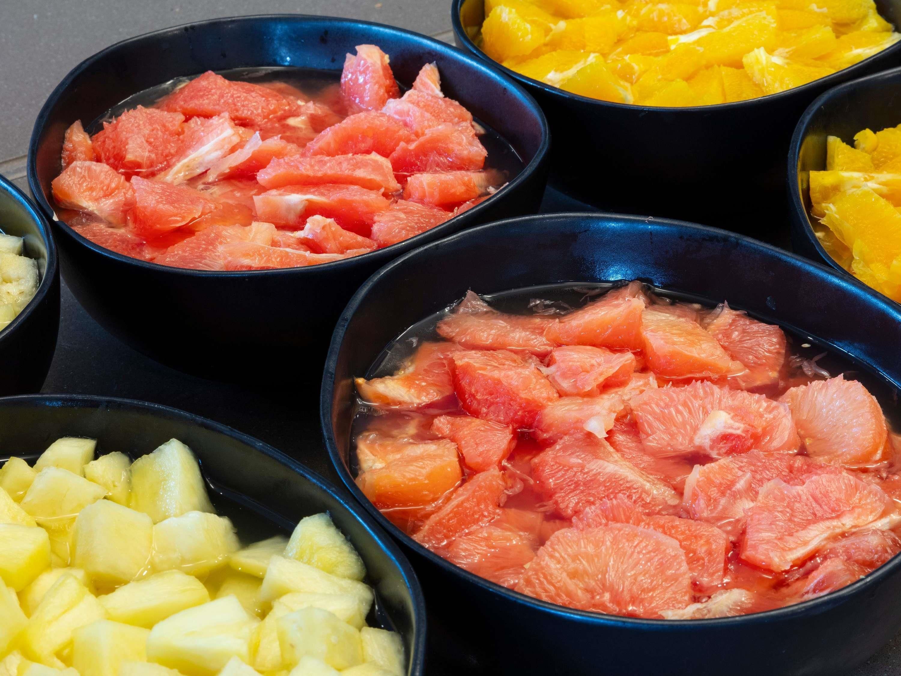 Bowls of fruit including grapefruit, pineapple, and mango.