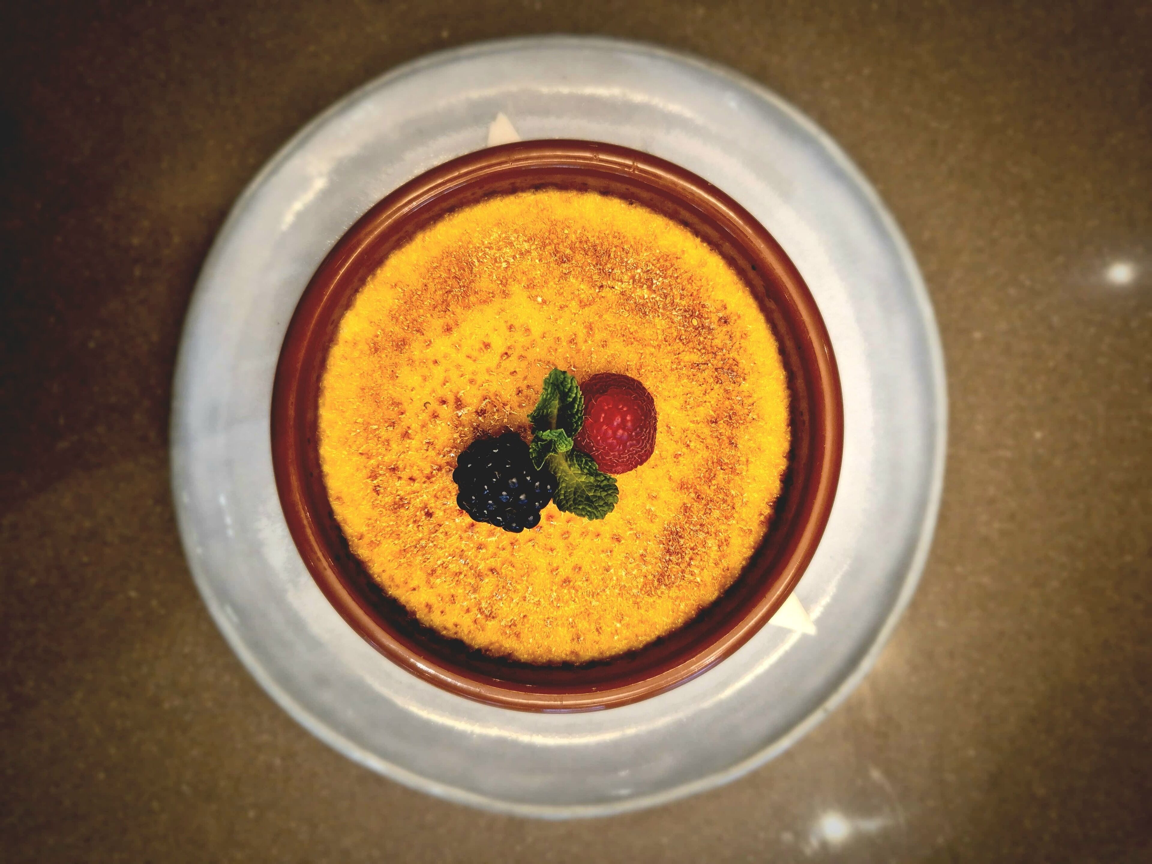 Un dessert servi dans un bol, garni de framboises et de mûres.