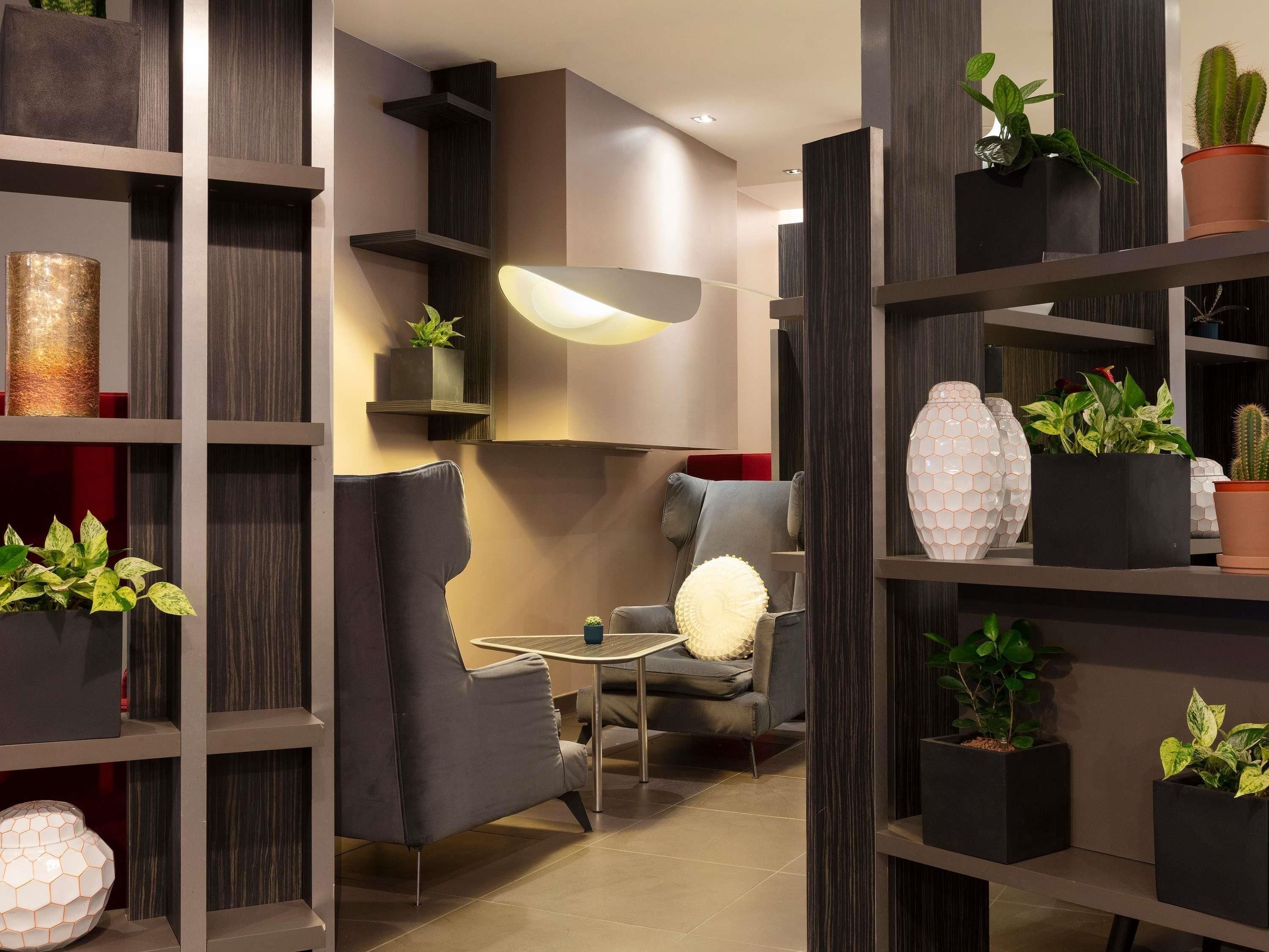 A modern interior with a sofa, a small table, and shelves with plants and decorative items.