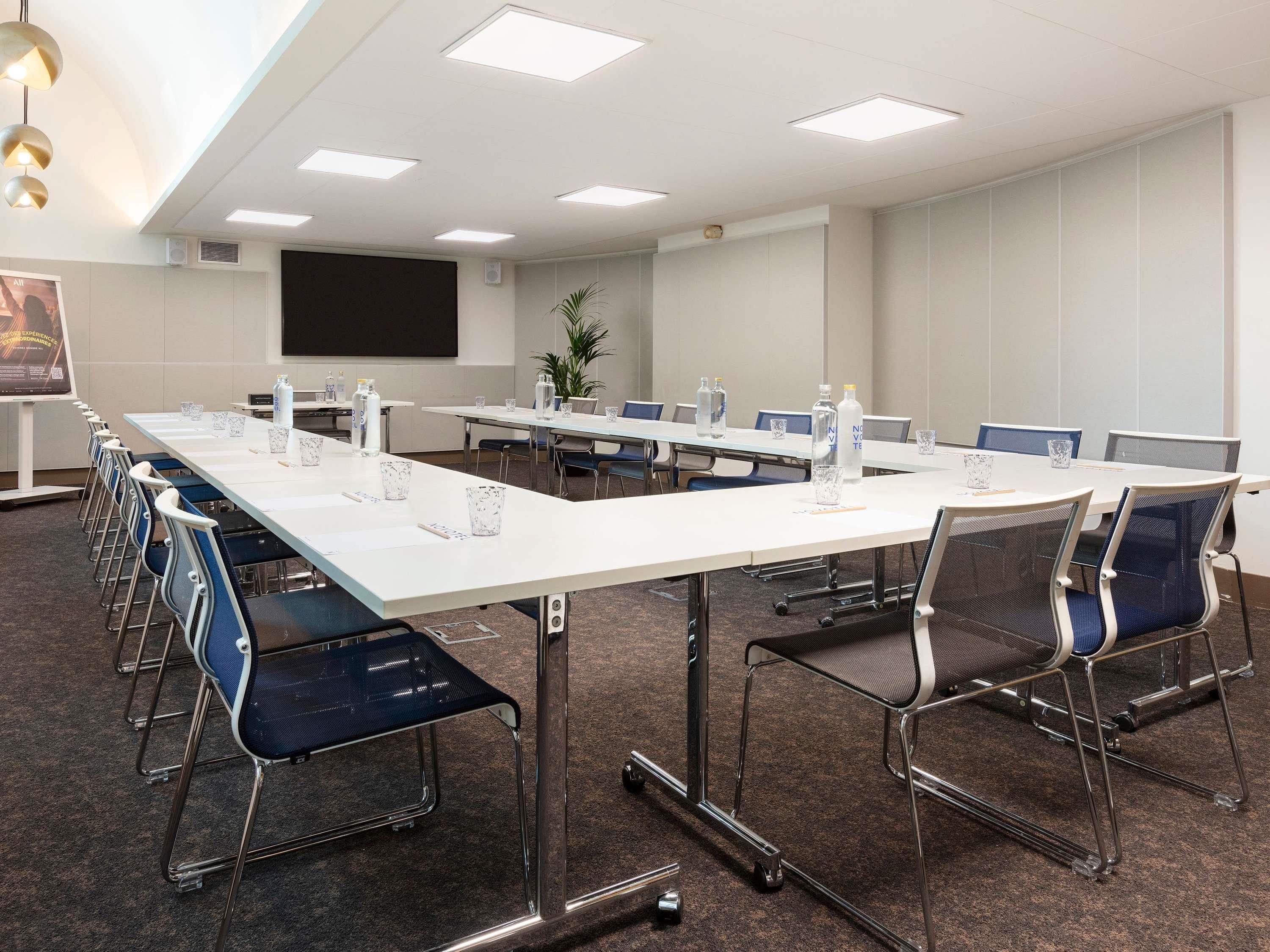 Une salle de conférence équipée de longues tables, de chaises et d’un écran de projection.