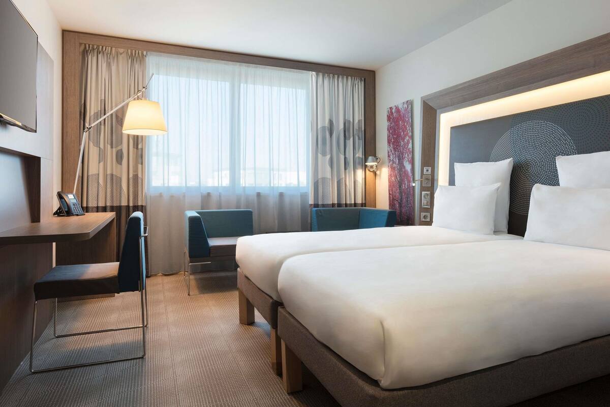 Una habitación de hotel con una cama grande, un escritorio con teléfono, una silla y una lámpara.
