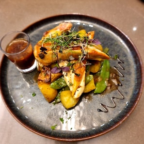 A plate of food with a glass of sauce on a ceramic plate.