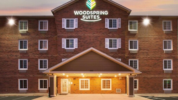 A brick building with a sign reading "WOODSPRING SUITES" and a number "3205" on the facade.