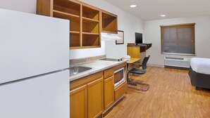 A compact kitchen with wooden cabinets, a built-in oven, and a large window with blinds.