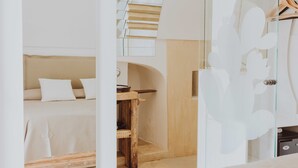 A modern bedroom with a bed, a wooden table, and a glass door with a white floral design. - Badia del Casale (Ugento)